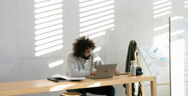 Studierender arbeitet am Laptop in einem lichtdurchflutetem Raum