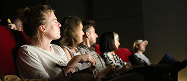 Eine Gruppe von Menschen sitzt im Kino und schaut auf die Leinwand