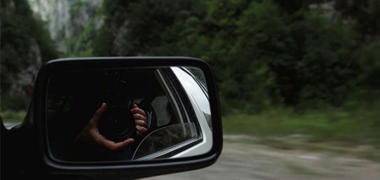 Hand, die eine Kamera hält, im Rückspiegel