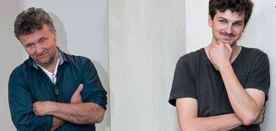 Dozent und Schüler scheinen etwas zu gemeinsam schmunzelnd zu betrachten