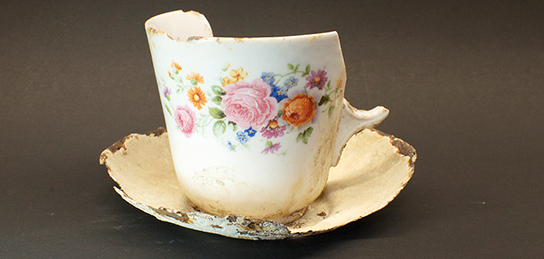 kaputte Porzellan Tasse mit farbigen Blumen bemalt