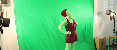 Eine Person, die vor einer grünen Leinwand posiert