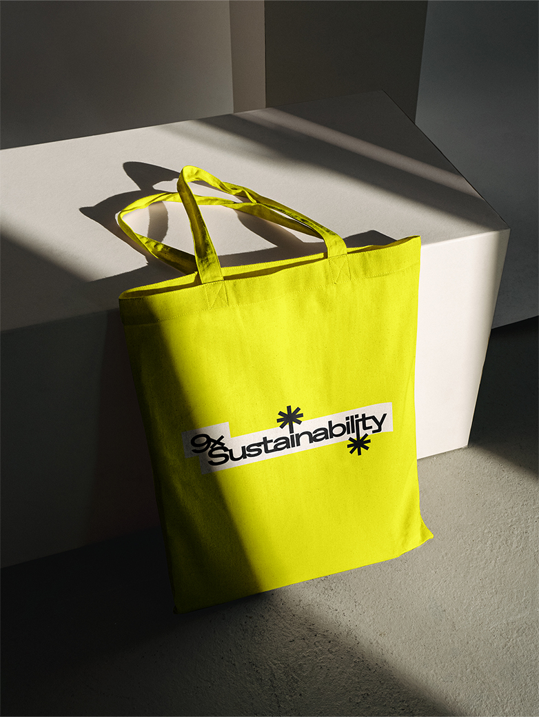 Eine gelbe Tasche lehnt an einen weissen Block, auf der Tasche steht das Logo von 