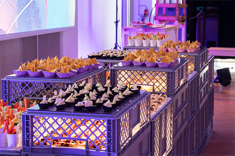 Apéro und Veranstaltung der Food installation Helga Luzern 2024: modulare Snack-Installation aus gestapelten Kisten, Publikum im Austausch sowie Einblicke in Präsentation und Eventsetting.