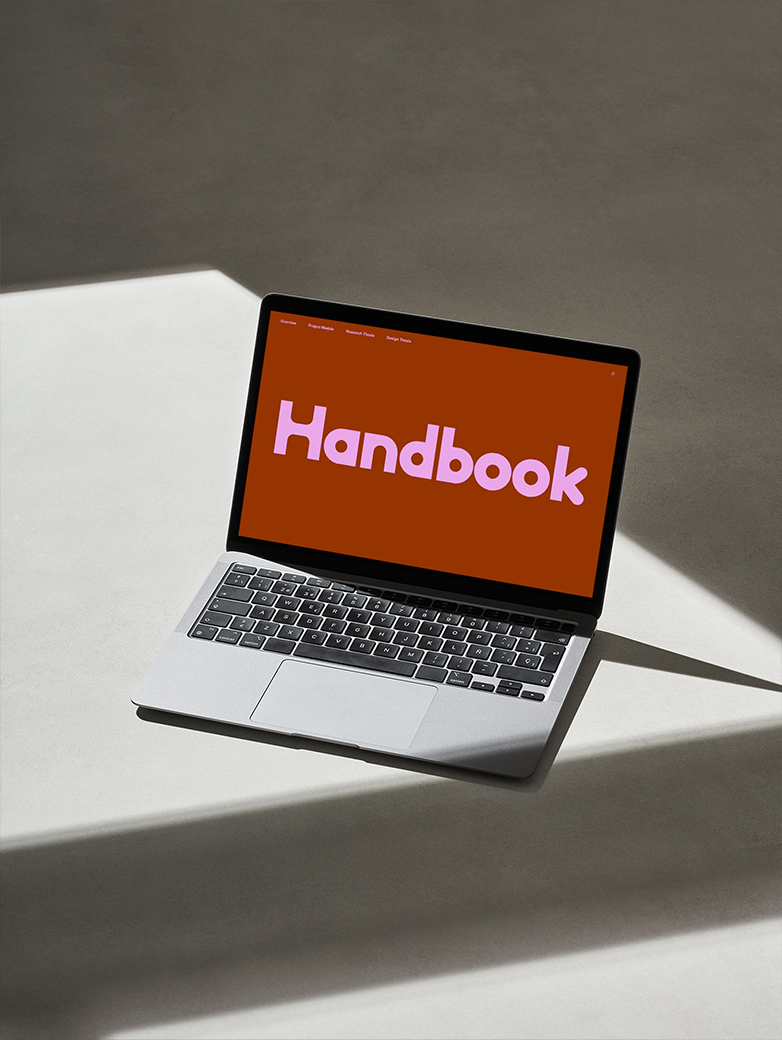 Ein Computer, der das Logo vom Handbook zeigt, eine weinroter Hintergrund mit pinker Schrift. Im Hintergrund gibt es ein Schattenspiel. 