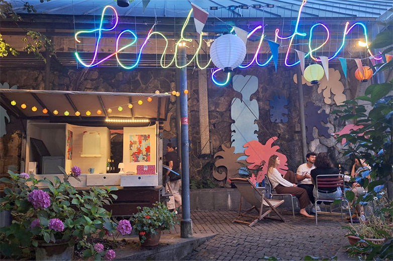 Bunt gestaltete Plakate und Drucksachen im öffentlichen Raum sowie Szenen eines lebendigen Quartiertreffs mit Menschen, Pflanzen und gemeinschaftlichen Aktivitäten im Aussenbereich.