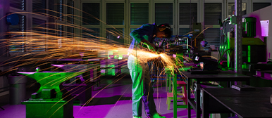 Metallbearbeitung in der Werkstatt – Studierender der HSLU Design Film Kunst bei praktischer Arbeit mit Funkenflug.
