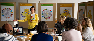 Eine Frau in einem gelben Pullover hält einen Vortrag zu Design Management. 