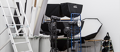 Ein Raum mit einer Leiter, Videolichtern, Gewichten und Hintergrundpanels. 