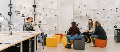 Eine Gruppe hockt vor einer Wand, die an ein Mindmap erinnert.