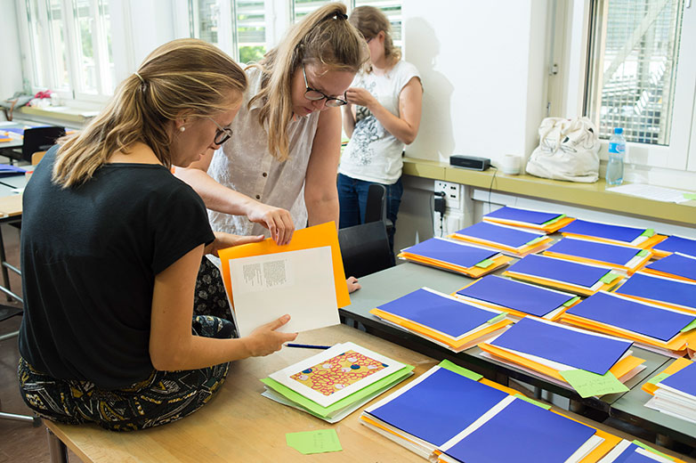 Alles Handarbeit: Studentinnen begutachten fertige Musterbuch-Seiten Bild: Hochschule Luzern/Priska Ketterer