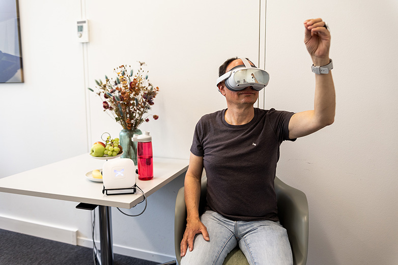 Mann mit einer VR-Brille mach eine Handbewegung in der Luft.