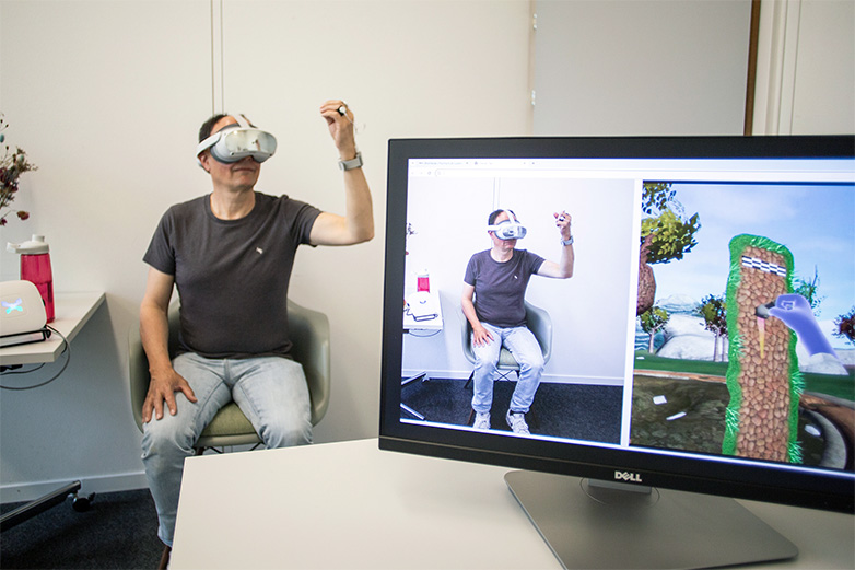 Mann mit einer VR-Brille hinter einem Bildschirm