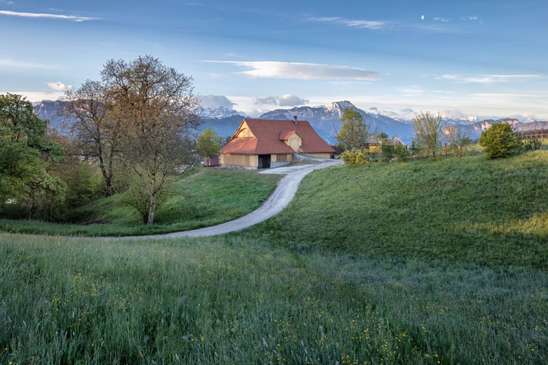 Saniertes Bauernhofgebäude umgeben von Land und Berglandschaft