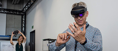 Ein Mann trägt eine VR-Brille, eine Frau hält eine VR Brille in die Höhe
