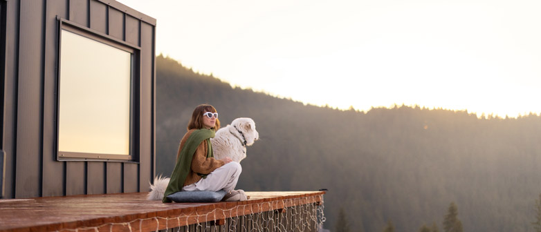 Frau und Hund auf Terasse schauen in Sonnenuntergang 