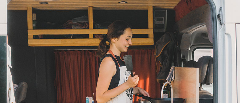 Frau steht in einem Mobilehome und wäscht ab