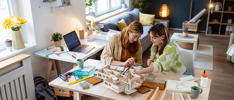 Zwei Frauen arbeiten an einem Architekturmodell