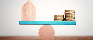 Waage mit Tiny House und Münzen