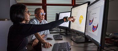 Woman and man sitting at various screens