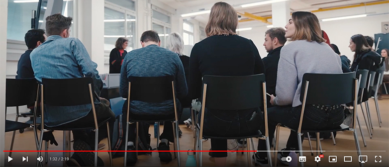 Menschengruppe von hinten, sitzend auf Stühlen