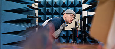 Person untersucht Gerät neben Schallisolationen
