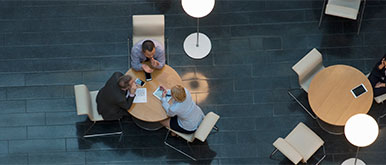 Drei Personen an einem runden Tisch von oben gesehen