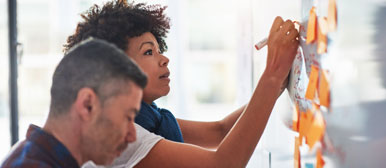 Eine Frau und ein Mann stehen an einem Flipchart