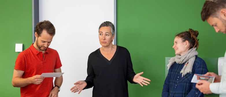 Männer und Frauen im Gespräch vor einer grünen Wand