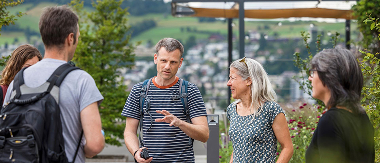 Menschen im Gespräch vor einigen Bäumen und Pflanzen im Hintergrund