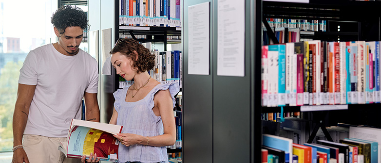 Ein Student und eine Studentin schauen zusammen in ein Buch