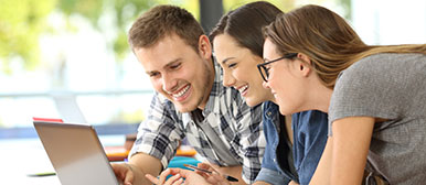 Drei junge Menschen schauen auf einen Laptop