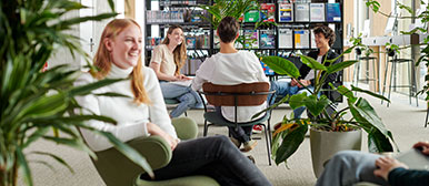 Schülerinnen sitzen in einer Bibliothek und sprechen miteinander