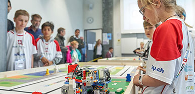 Kinder schauen einem Roboter auf einem Tisch zu