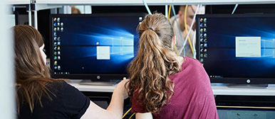 Zwei Frauen von hinten vor ihren Bildschirmen