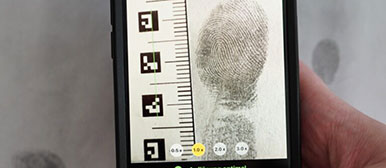 Eine Hand hält ein Handy , das Fingerabdrücke analysiert