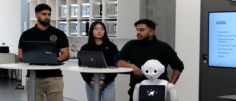 Drei Studierende halten einen Vortrag und der Roboter Pepper steht im Vordergrund