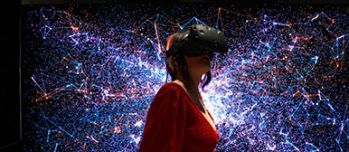 Eine Frau trägt eine Virtual-Reality-Brille, im Hintergrund sind farbige Punkte und Linien zu sehen.