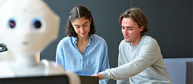 Weisser Roboter im Vordergrund, im Hintergrund ein Mann und eine Frau