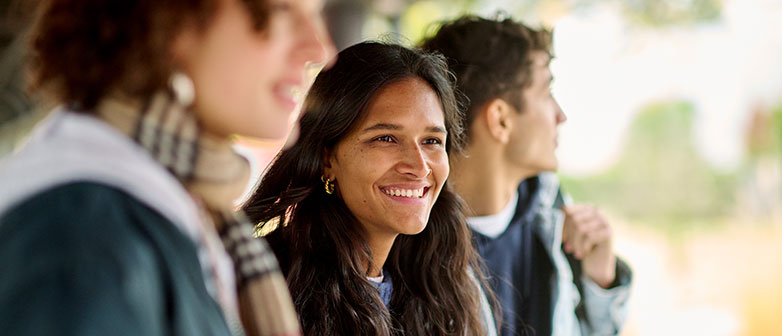 Drei Studierende, seitlich fotografiert und lächelnd