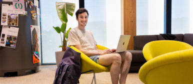Ein Student sitzt lächelnd auf einem gelben Sessel