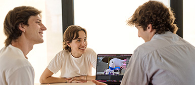 Drei Studierende besprechen eine 3D-Figur auf dem Laptop