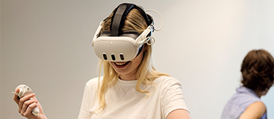 Eine lachende Studierende trägt eine VR-Brille