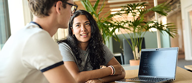 Zwei Studierende besprechen einen Code auf dem Laptop