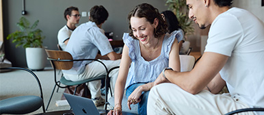 Zwei Studierende besprechen etwas am Laptop