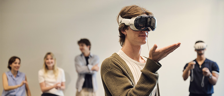 Ein Student trägt eine VR-Brille und hebt seine Hand