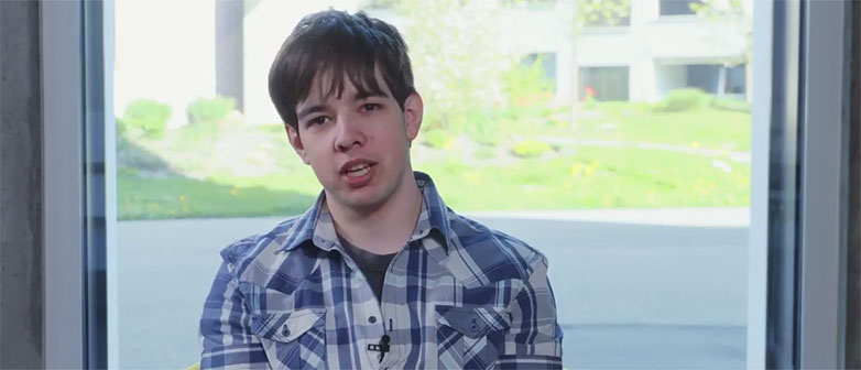 Portrait eines Wirtschaftsinformatik-Studenten vor einem Fenster, durch das man die Natur sieht