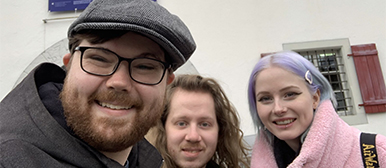 Drei Studierende schauen in die Kamera