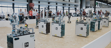 Eine Halle voller Tische auf denen Roboter stehen