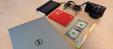 Notwendige Reiseutensilien: Laptop, Kamera, Sonnenbrille, Pass, Dollar, Zahnbürste und Notizbuch